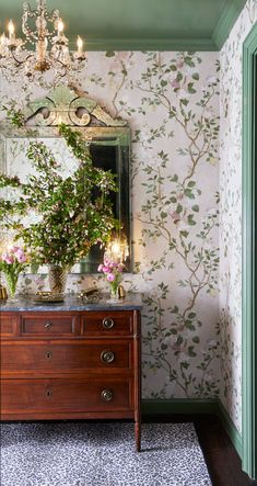 a dresser and mirror in a room with floral wallpaper on the walls behind it