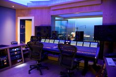 an empty recording studio with multiple monitors and sound equipment on the desk in front of large windows