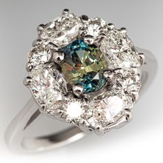 a fancy ring with an aqua and white diamond center surrounded by smaller round brilliant cut diamonds