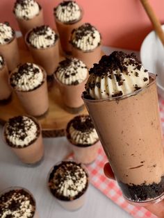 a person holding up a cupcake with whipped cream and chocolate sprinkles