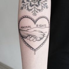 a tattoo on the arm of a woman with an animal rights heart and two hands holding each other