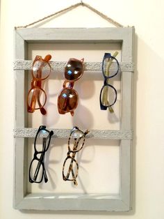 the diy eyeglass organizer is made from an old window frame and has five pairs of glasses hanging on it