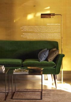 a green couch sitting next to a table on top of a hard wood floor in front of a yellow wall