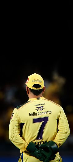 a man wearing a yellow jersey and green gloves standing in front of a black background