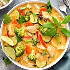 a white bowl filled with chicken and veggies next to a plate of rice