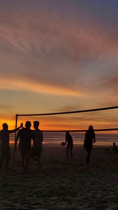 people playing volleyball on the beach at sunset