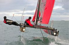 two men in red jackets are sailing on the water