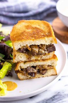 a sandwich cut in half sitting on top of a white plate next to a salad