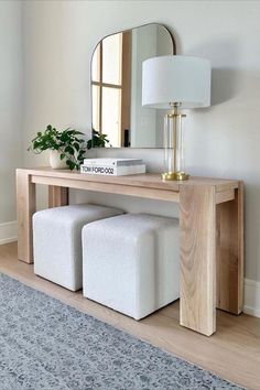 a wooden table with two stools underneath it and a mirror on the wall behind it