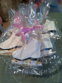 several pairs of shoes wrapped in plastic on top of a glass table with pink ribbon