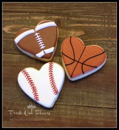 three decorated cookies in the shape of heart shaped sports balls and a basketball on them