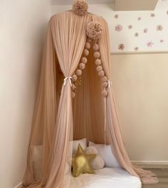 a canopy bed with pink drapes and pom poms