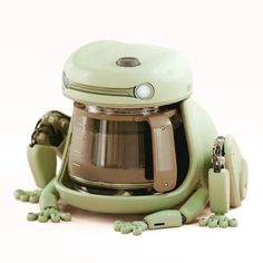 a green frog is sitting next to a coffee pot with its legs spread out and eyes closed