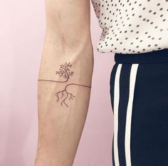 a woman's arm with a small tree tattoo on the left side of her right arm