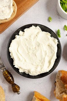 a black bowl filled with cream cheese next to bread