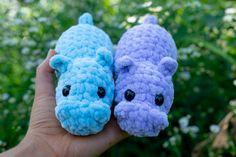 two small crocheted animals sitting on top of each other in front of some flowers