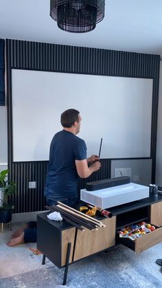 a man standing in front of a projector screen holding a paint roller and brush