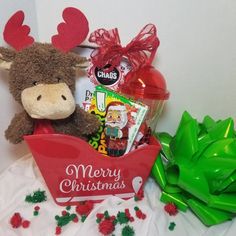 a stuffed moose sitting next to a christmas gift basket filled with candy and candies