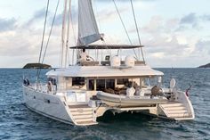 a white catamaran sailing in the ocean with people on it's deck