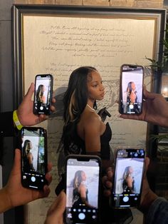 several people holding up their cell phones in front of a wall with writing on it