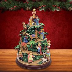 a christmas tree with figurines on top of it in front of a red background