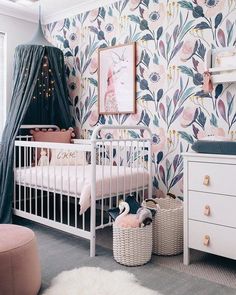 a baby's room with floral wallpaper and white furniture, including a crib