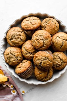 a bowl filled with muffins on top of a white table next to a banana