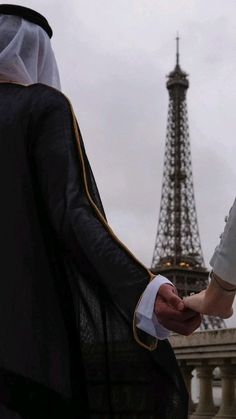 two people holding hands with the eiffel tower in the background