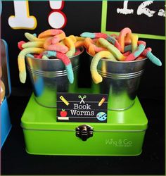 two buckets filled with candy worms sitting on top of a green box