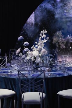 the table is set with white flowers and blue cloths for an elegant dinner party