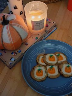 there are some cookies on the plate next to a candle and pumpkins in the background