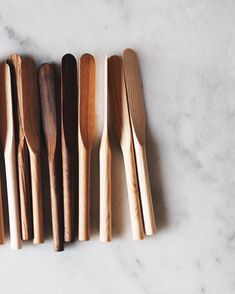 five wooden spoons lined up on a marble surface