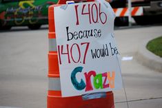 a sign that is on the side of a road in front of a traffic cone