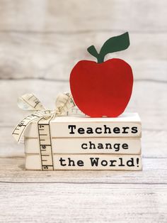 an apple sitting on top of a stack of books that says teachers change the world