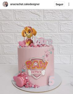 a pink birthday cake with a dog on top and paw patrol decorations in the middle