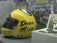 a yellow motorcycle helmet sitting on top of a table next to a sign that says, dear moon