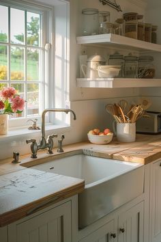 a kitchen sink sitting under a window next to a wooden counter top with utensils on it