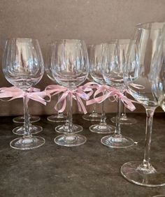 six wine glasses with pink bows are lined up in a row on a counter top