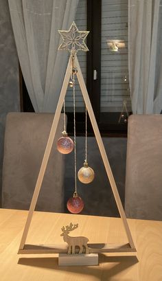 a wooden christmas tree with ornaments hanging from it's sides on top of a table