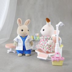 two stuffed animals sitting next to each other near a toy dentist's chair and sink