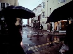 people walking down the street in the rain with umbrellas