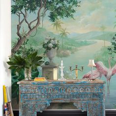 a room with a painting on the wall next to a blue table and vases