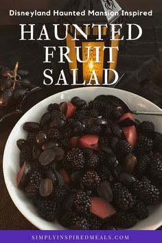 a white bowl filled with fruit next to a candle