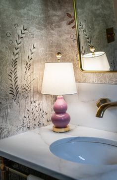 a pink lamp sitting on top of a bathroom sink next to a white countertop