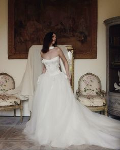 a woman in a white wedding dress standing next to a chair