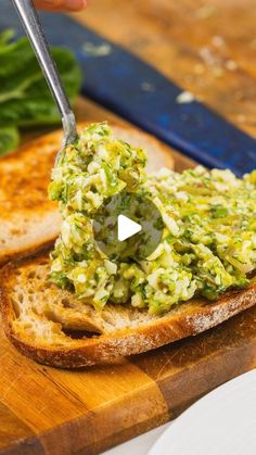 someone is spreading guacamole on top of toasted bread with a knife