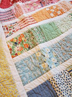 a colorful quilt is laying on top of a bed sheet that has many different colors and patterns