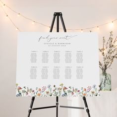 an easel with a seating chart on it in front of a string of lights