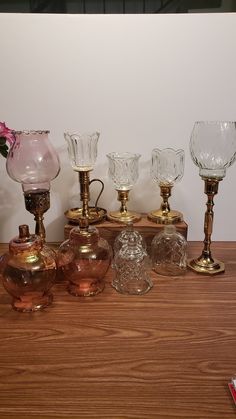 there are many different glass vases on the table next to each other and one has a pink flower in it