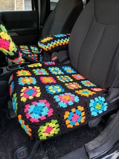 a car seat covered in a crocheted blanket and two matching pillow cases with colorful flowers on them